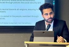 Advocate and author Nikhil Chugh delivering a legal literacy presentation at a conference with a microphone and laptop.