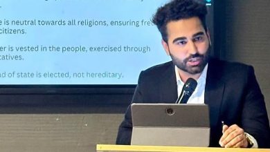 Advocate and author Nikhil Chugh delivering a legal literacy presentation at a conference with a microphone and laptop.