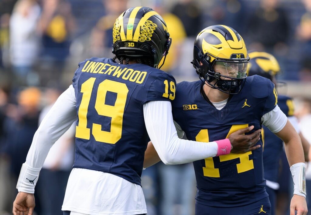 Michigan quarterback's Bryce Underwood (19) and Tommy Carr (14) exchange pleasantries during pregame warmups before